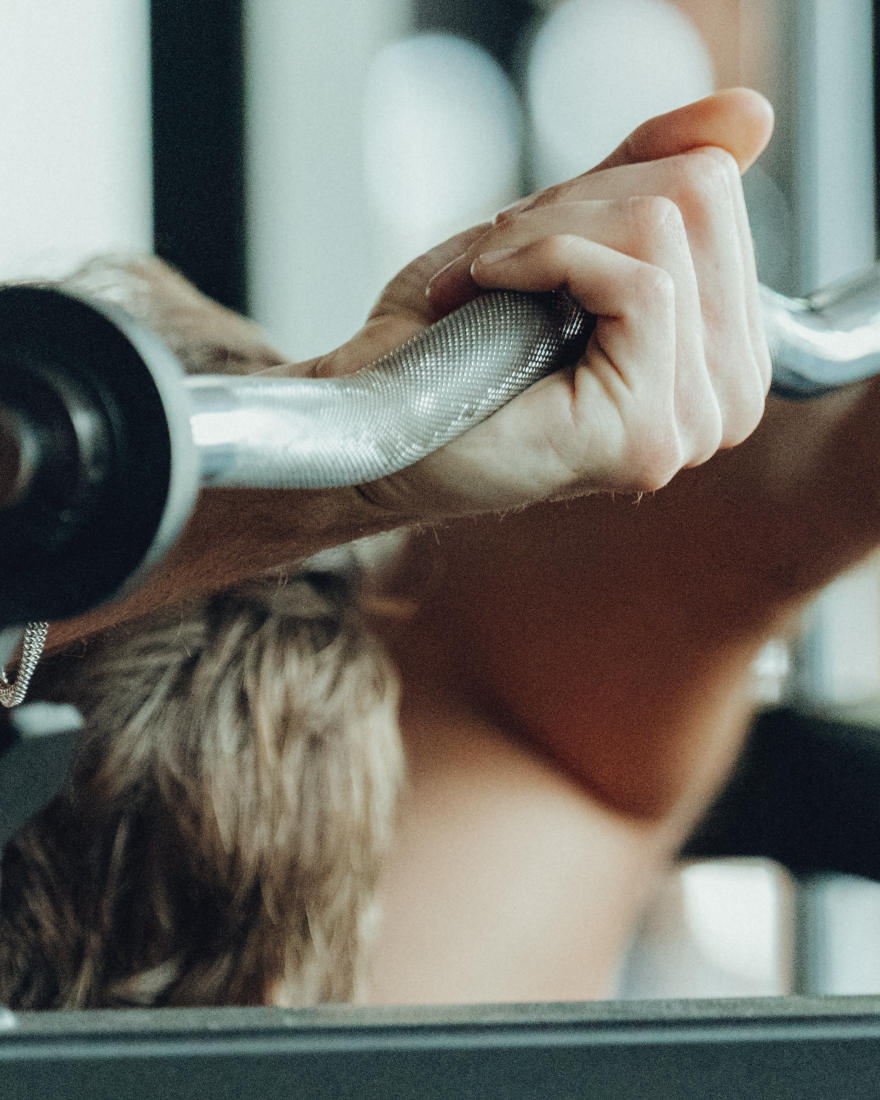 A member pressing a barbell overhead at The Forum